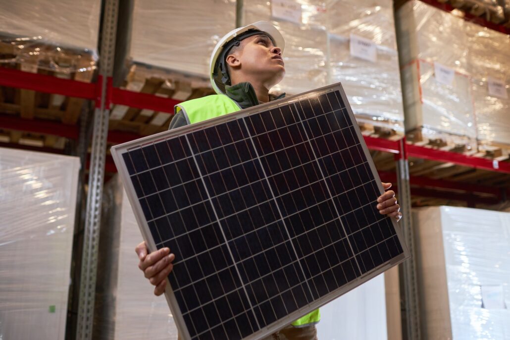 Female worker carrying solar panel at indoor warehouse