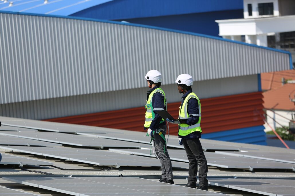 Solar panel installer installing solar panels on roof of warehouse