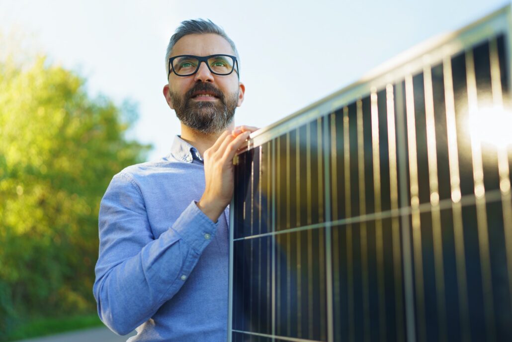 Businessman holding solar panel, standing outdoor at garden.