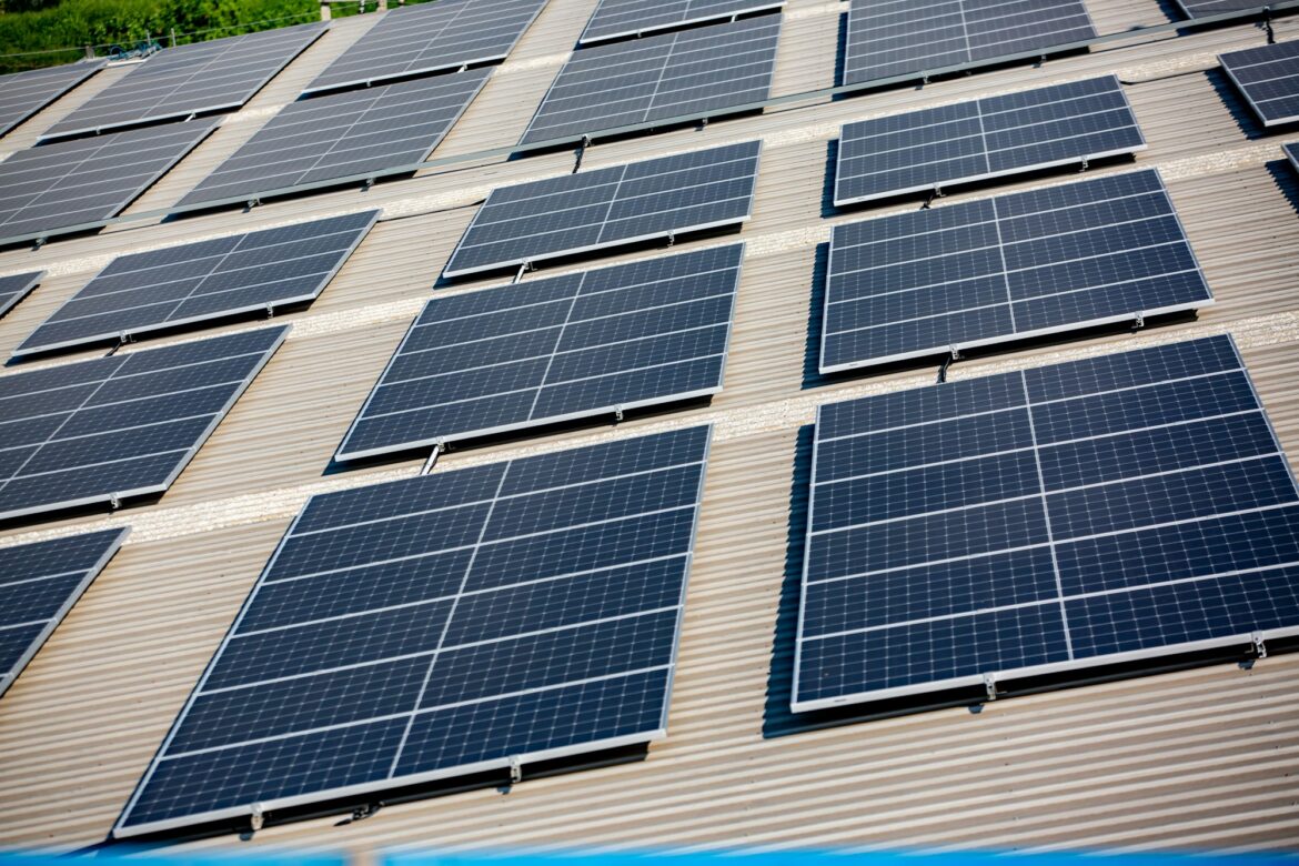 Solar panel installer installing solar panels on roof of warehouse