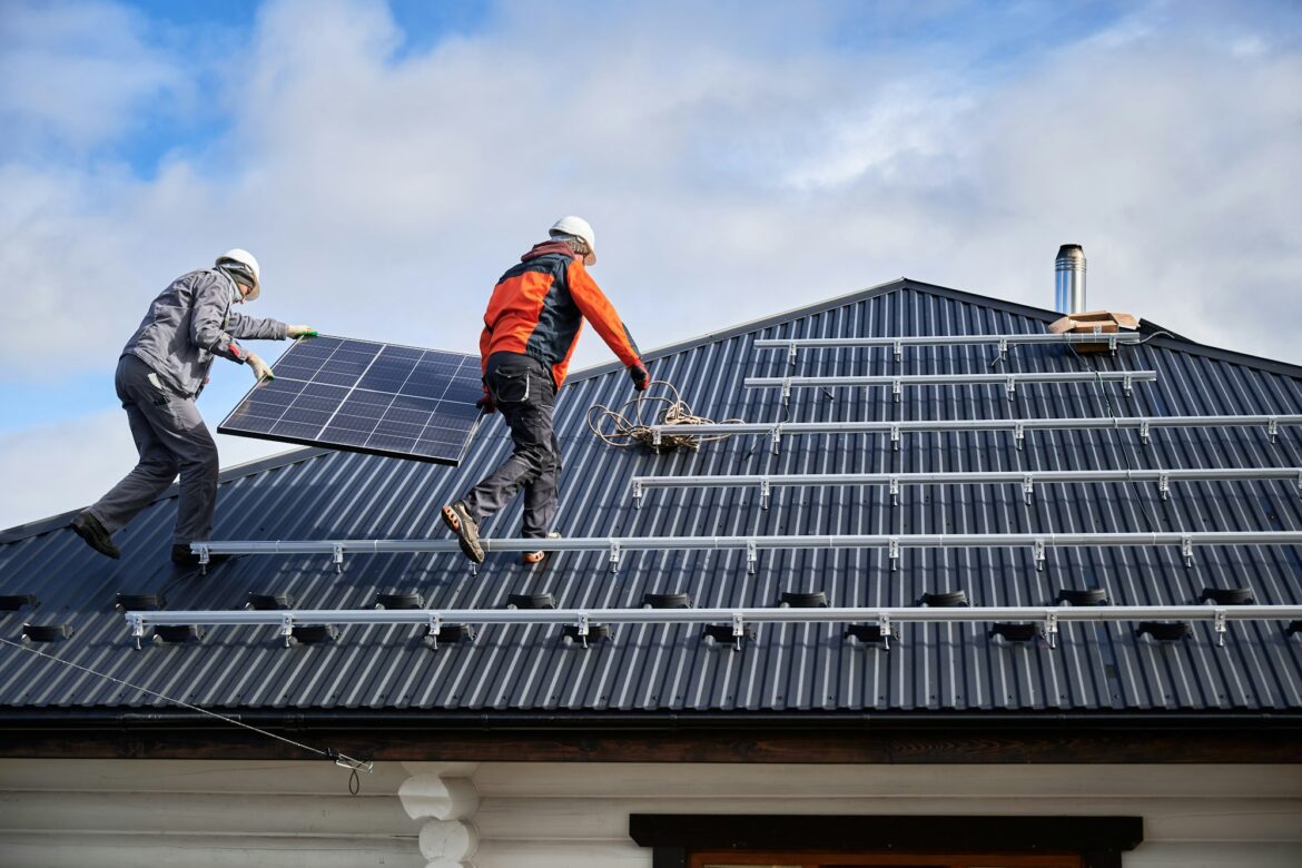 Workers carrying solar panel on a roof of house