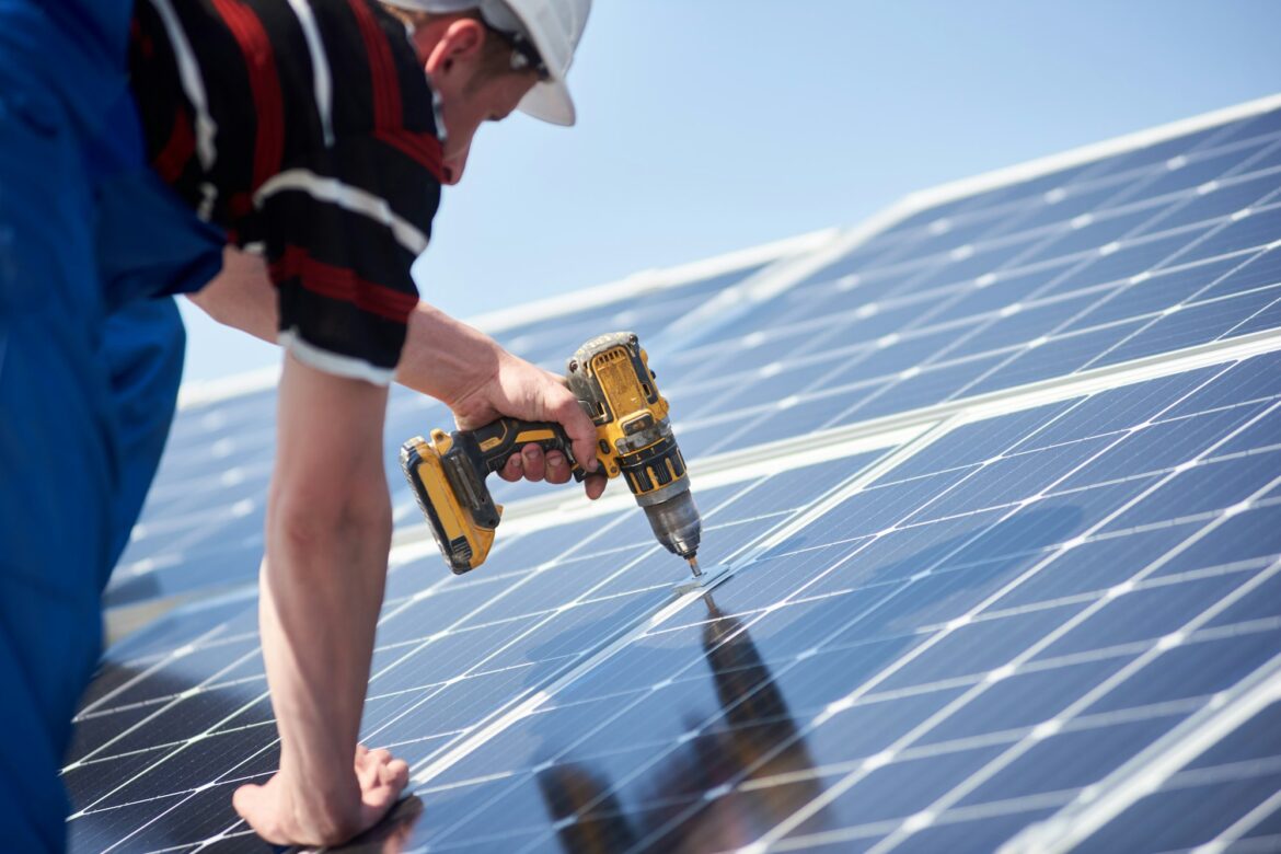 Electrician mounting solar panel on roof of modern house