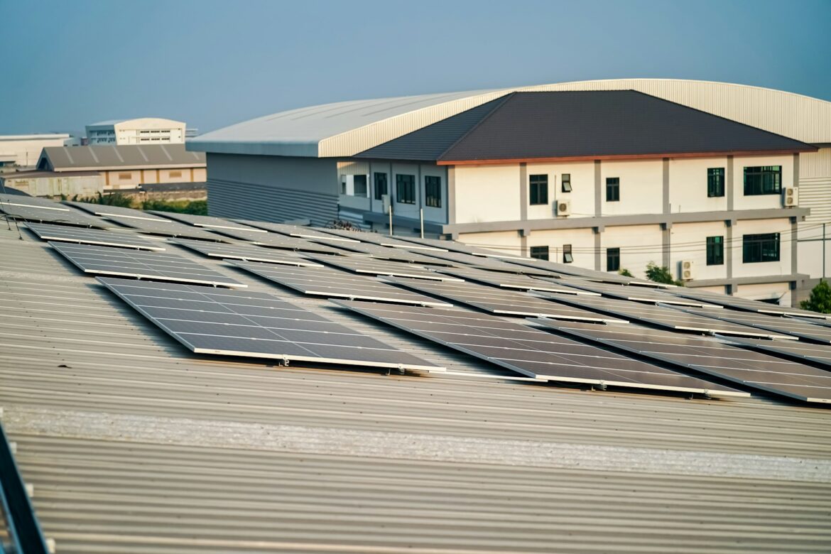 Solar panel installer installing solar panels on roof of warehouse