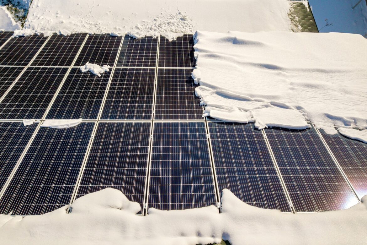 Close up surface of a house roof covered with solar panels in winter with snow on top. Energy