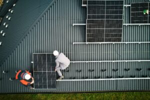 Men workers installing solar panels on roof of house.